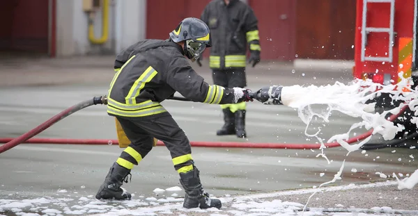 Pompiers tout en éteignant le feu avec de la mousse — Photo