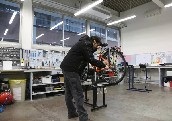 Jovem mecânico reparando a roda da bicicleta dentro do mec — Fotografia de Stock