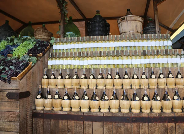 Винные бутылки с ковбоями и виноградом в винном погребе — стоковое фото