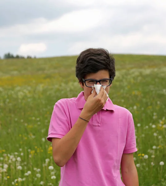 Allergic boy with glasses blows his nose using a white handkerch — Stock Photo, Image