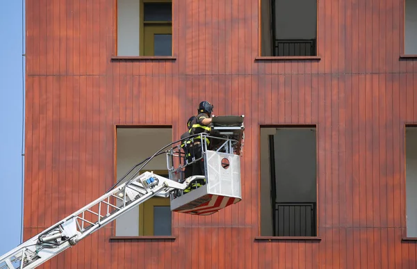 Bomberos durante el ejercicio en la estación de bomberos y el edificio —  Fotos de Stock