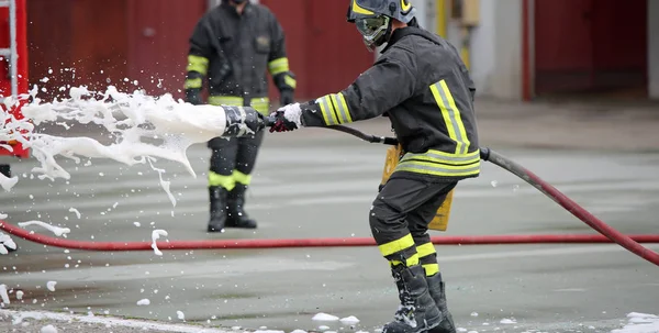 Pompiers tout en éteignant le feu avec de la mousse — Photo