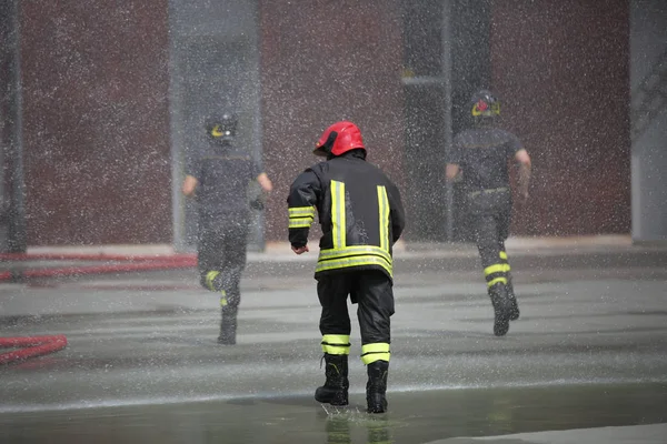 Feuerwehrleute unter den Wasserspritzern — Stockfoto