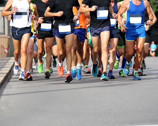 Muscular legs of athletes running the marathon on the city stree