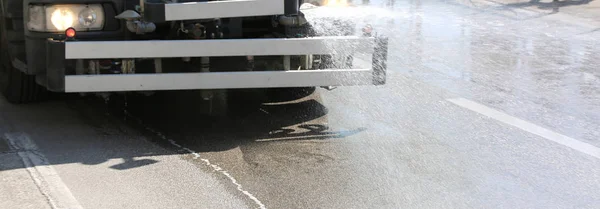 Water splash van vrachtwagen voor het wassen van de stedelijke wegen — Stockfoto