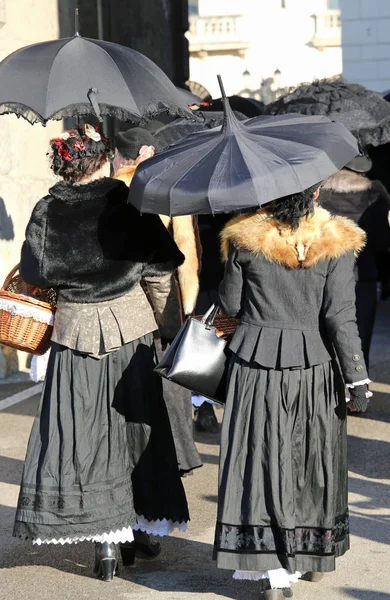 Frauen in Vintage-Kleidung und einem schwarzen Regenschirm zum Schutz — Stockfoto