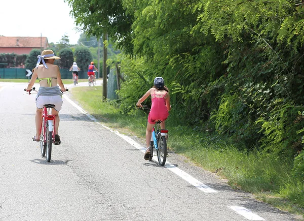 Famille avec maman et jeune fille pédale sur la route pavée — Photo