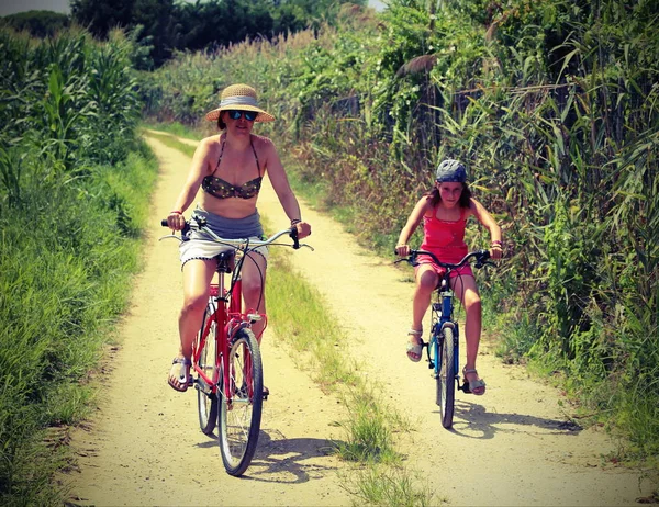 Jovem mãe e menina em bicicletas na estrada estreita — Fotografia de Stock