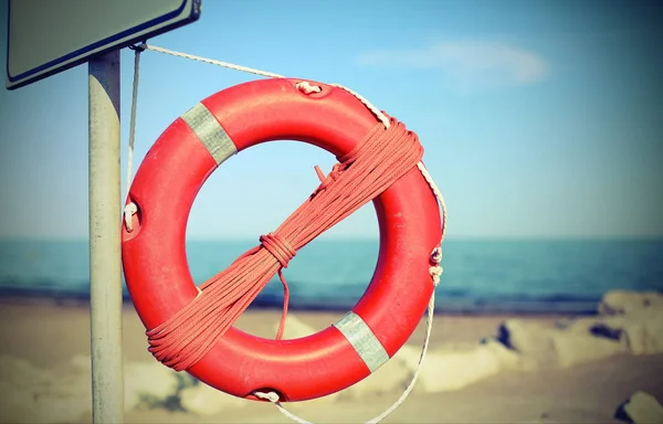 Orange lifebuoy for people near rocks at the sea in summer — Stock Photo, Image