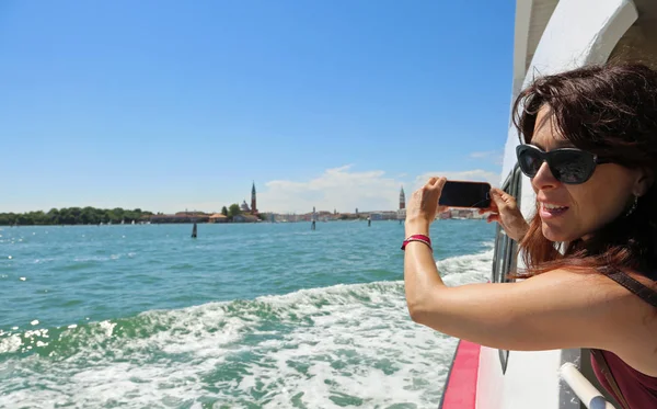 Woman takes picture of Venice in Italy by boat in the sea — Stock Photo, Image