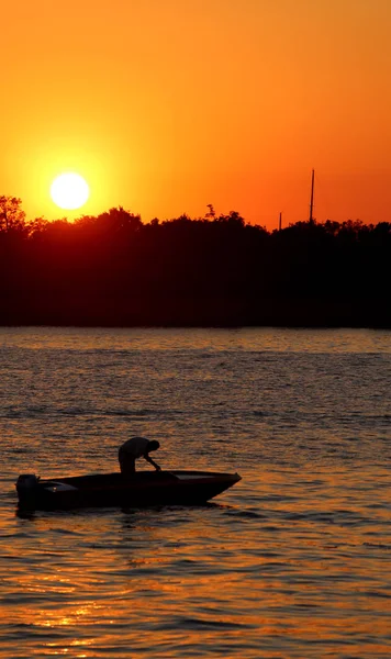 Big orange sun at sunset and the boat of fisherman
