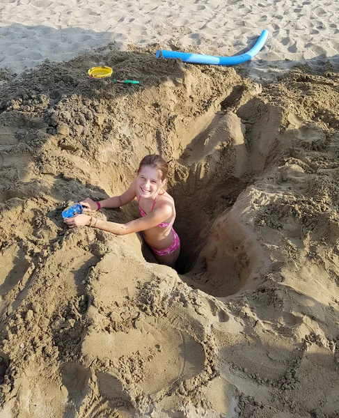 Liten flicka spelar på ett hål i stranden — Stockfoto