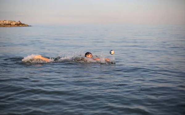Fiatal fiú játszik a tengeren a vízilabda nyári — Stock Fotó