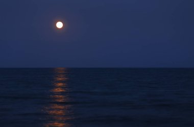 Kırmızı dolunayda deniz ufukta