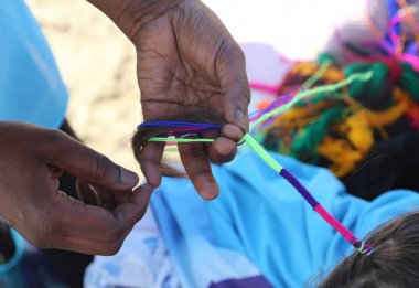 Afrikalı kadın el ile küçük bir kızın saç interlaces 