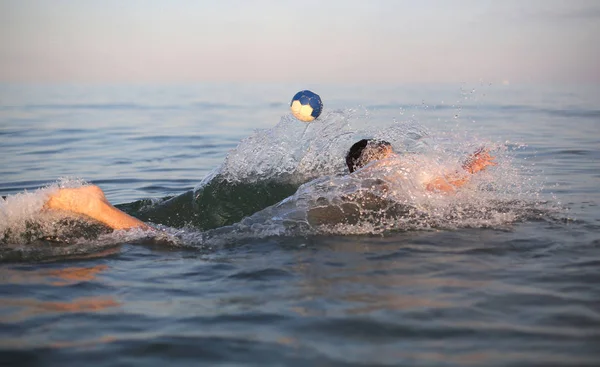 Ung pojke spelar vattenpolo i havet — Stockfoto