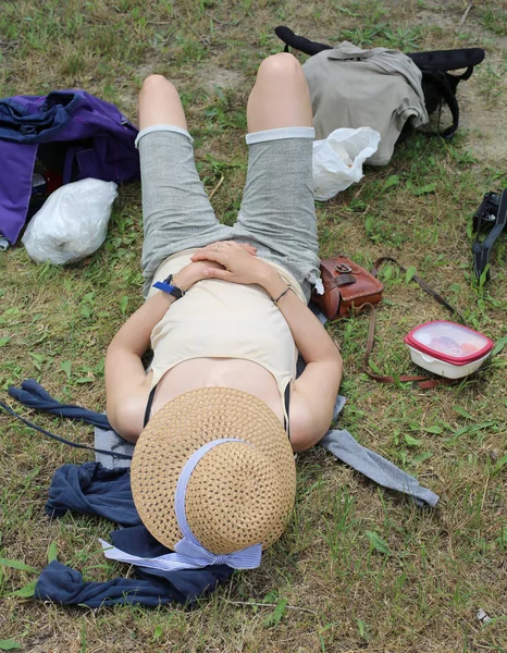 Vrouw met een grote stro hoed en ontspant ze na picknick op de l — Stockfoto