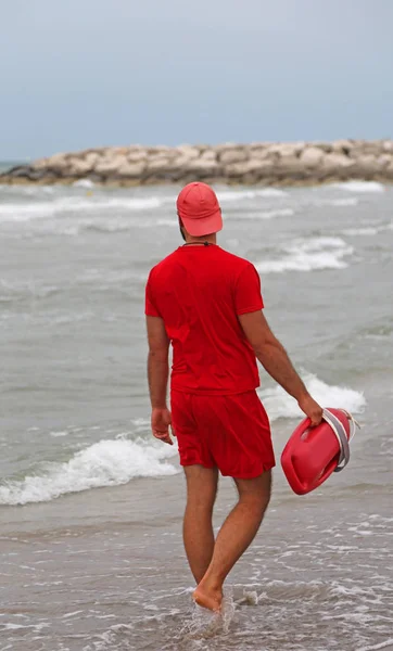 Salvavidas con uniforme rojo comprueba los bañistas con el resistente se — Foto de Stock