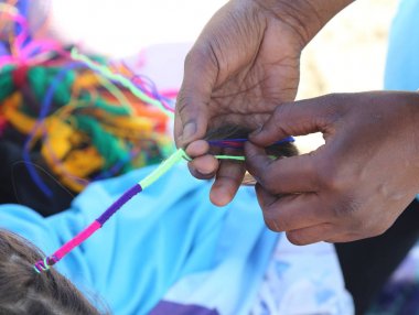 Afrikalı kadın el ile küçük bir kızın saç interlaces 