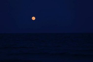 Kırmızı dolunayda deniz ufukta