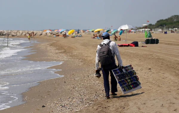 Armer Straßenverkäufer mit Kleidung und Kleidern am Strand — Stockfoto