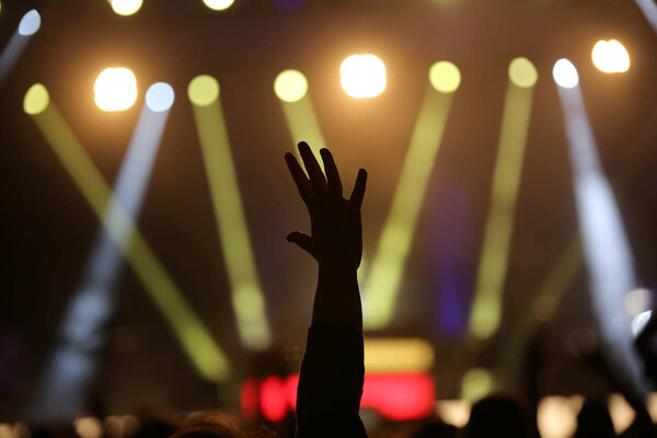 Live concert and hand raised during the performance of a musical ensemble with many lights and spotlights