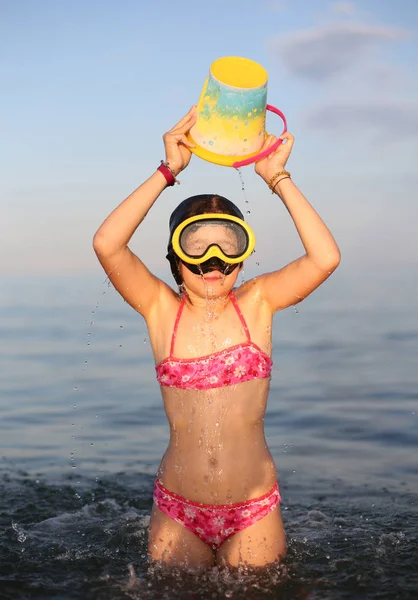 Hübsches kleines Mädchen im Badeanzug spielt mit Eimer voll Wasser — Stockfoto