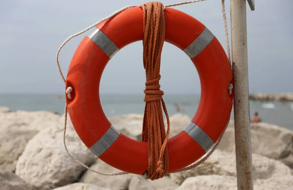 Big red buoy on the rocks to help swimmers — Stock Photo, Image