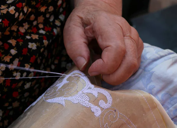 Manos de una anciana bordando un encaje con tombolo y c — Foto de Stock