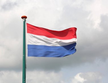 Beyaz ve mavi kırmızı ve bulutlu gökyüzü ile Hollanda bayrağı sallayarak