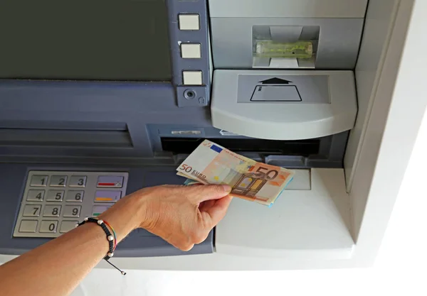 Hand of young woman while withdrawing banknotes 50 euros from an — Stock Photo, Image