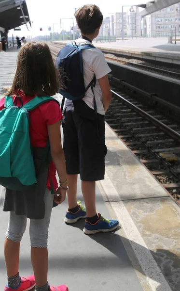 Брат и сестра с рюкзаками ждут поезда — стоковое фото