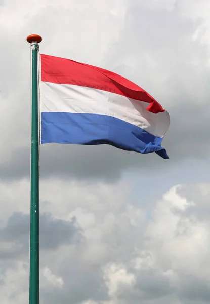 Bandeira holandesa acenando com fundo céu nublado — Fotografia de Stock