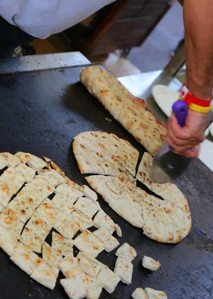 Hand av kocken samtidigt minska det platt brödet som även kallas piadina i — Stockfoto