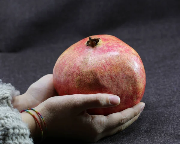 Hand of young girl holding a large ripe pomegranate — Stock Photo, Image