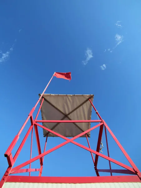 Alta torre de salva-vidas na praia com a bandeira vermelha — Fotografia de Stock