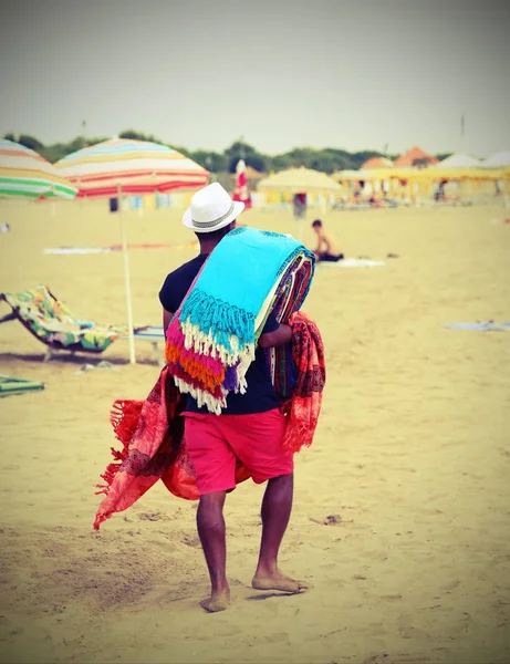 Caminhante abusivo andando na praia vendendo tecidos de algodão — Fotografia de Stock