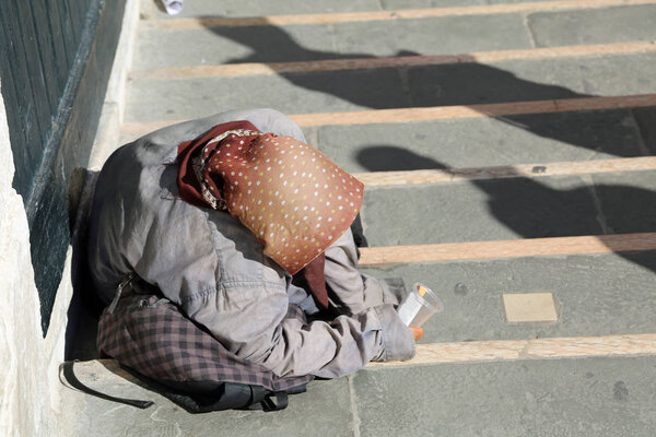 gypsy with headscarves on her head and long skirt calls alms