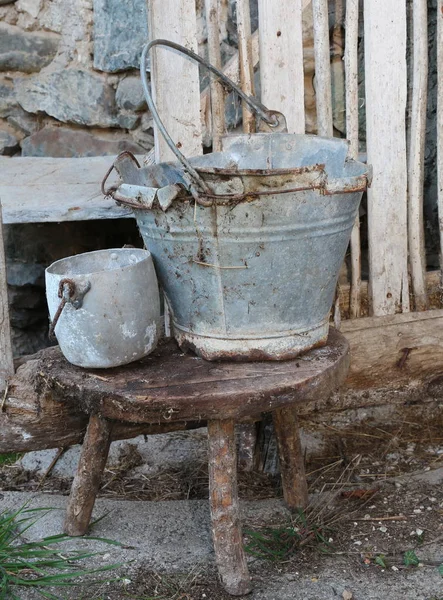 Balde de lata quebrado e uma panela sobre as fezes do antigo estábulo — Fotografia de Stock