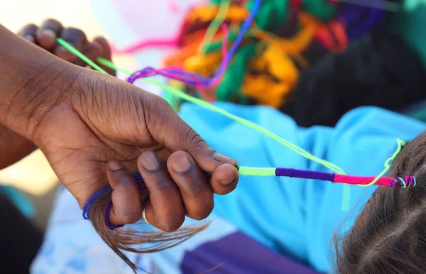 Afrikalı kadın el ile küçük bir kızın saç interlaces 