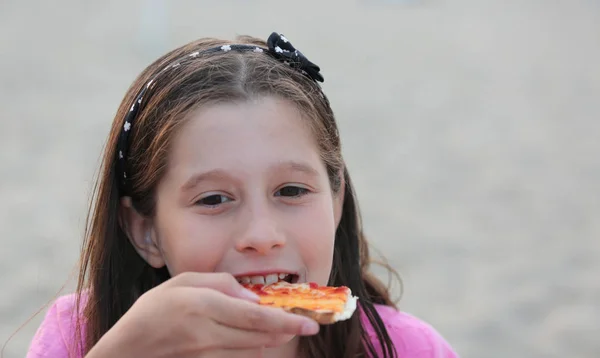 Dziewczynka kaukaski zjada pizza na plaży — Zdjęcie stockowe