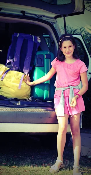 Улыбающаяся маленькая девочка грузит машину в багажник — стоковое фото