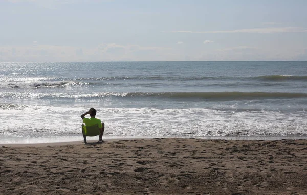 夏の海岸で孤独な若い男の子がかかっています。 — ストック写真