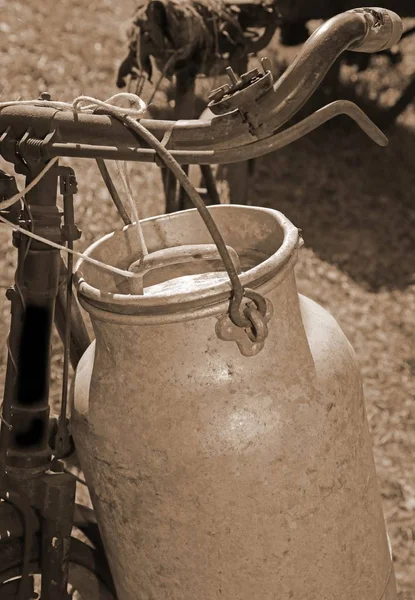 Молочник старый велосипед с банкой молока и древней сепией тонизирован — стоковое фото