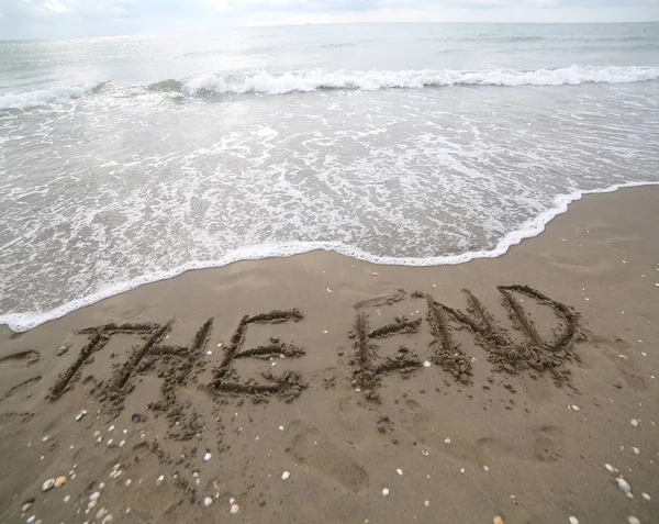 O texto final escrito na areia e a onda que está apagando t — Fotografia de Stock
