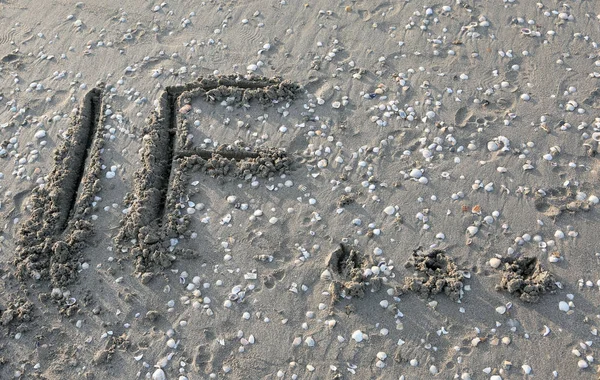 Text om på sanden i havet väntar på att raderas vid vattnet — Stockfoto