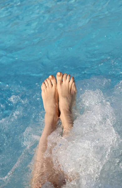 Barefoot voeten van een jonge vrouw tijdens de whirlpool in het zwembad — Stockfoto