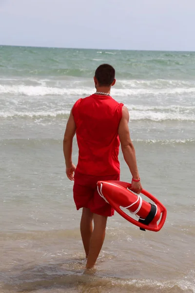 Bagnino muscolare a riva sulla riva del mare in spiaggia — Foto Stock