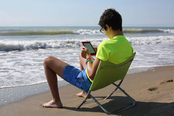 Młody chłopak czyta ebook nad morzem — Zdjęcie stockowe