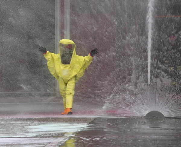 Homme avec une combinaison de protection et des éclaboussures d'eau pour refroidir le surro — Photo